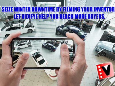 Person holding a smartphone, filming a showroom filled with vehicles.