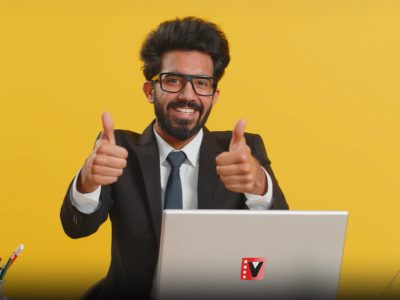 Salesman seated at a desk with a laptop, giving a thumbs-up, suggesting the effectiveness of Vidifye video ads.